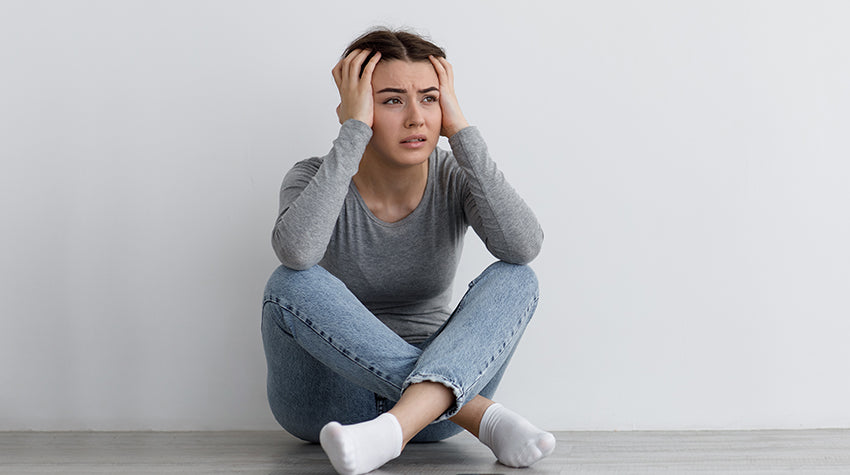 Stressed woman with hands on head in need of CBG for Anxiety with CBD tincture or CBD & CBG gummies.